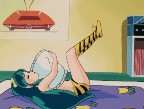 A Girl With Green Hair Is Laying On Her Stomach With Her Legs Up GIF