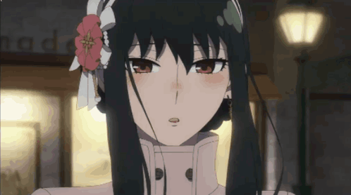 A Girl With Long Black Hair And A Flower In Her Hair Looks At The Camera GIF