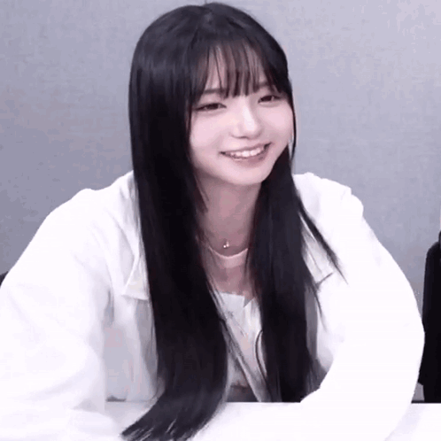 A Girl With Long Black Hair And Bangs Is Smiling GIF