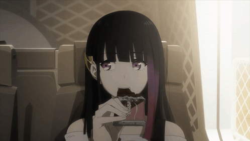 A Girl With Long Black Hair Is Sitting In A Chair Eating A Chocolate Bar GIF