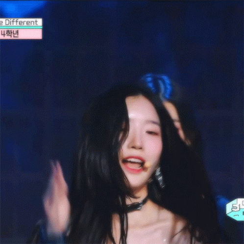A Girl With Long Black Hair Is Smiling In Front Of A Sign That Says ' E Different ' GIF