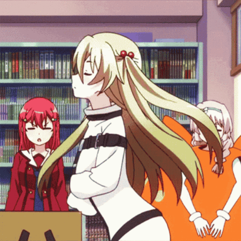 A Girl With Long Blonde Hair Stands In Front Of A Bookcase GIF