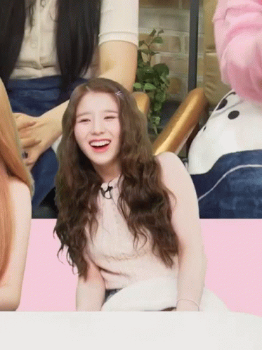 A Girl With Long Curly Hair Is Smiling In Front Of A Panda Bear GIF
