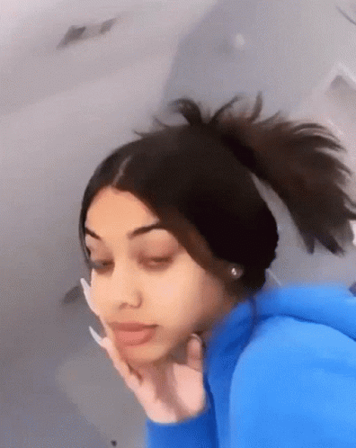 A Girl With Long Nails And A Ponytail Is Making A Funny Face . GIF