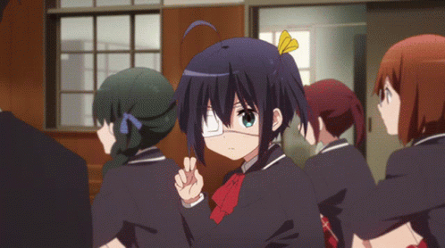 A Girl With One Eye And A Yellow Bow On Her Hair Stands In A Crowd Of People GIF