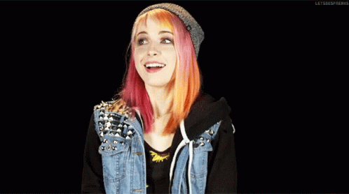 A Girl With Pink And Orange Hair Wearing A Denim Jacket And A Beanie GIF