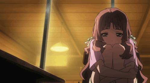 a girl with pink hair is hugging her knees in a dark room