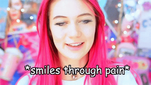 A Girl With Pink Hair Is Smiling With The Words * Smiles Through Pain * Below Her GIF