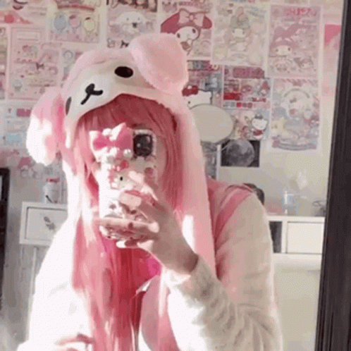 A Girl With Pink Hair Is Taking A Selfie In A Mirror While Wearing A Pink Hat . GIF
