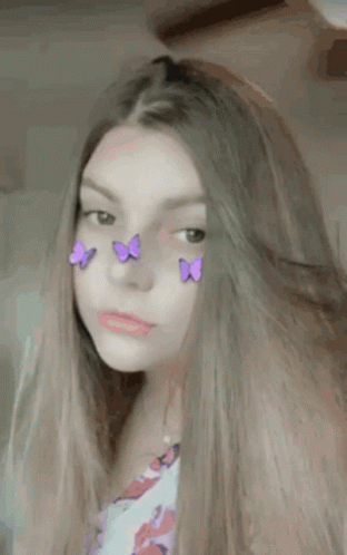 A Girl With Purple Butterflies On Her Face Is Looking At The Camera . GIF