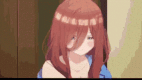 A Girl With Red Hair And A Blue Shirt Is Standing In A Room With A Blurred Background . GIF