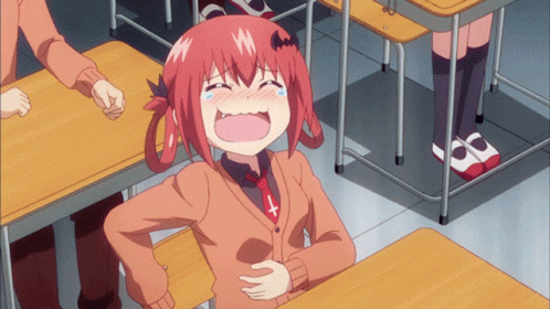 A Girl With Red Hair And A Cross On Her Shirt Is Laughing In A Classroom GIF