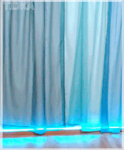 A Girl With Red Hair And Glasses Stands In Front Of A Blue Curtain With The Word Tdka Written On It GIF