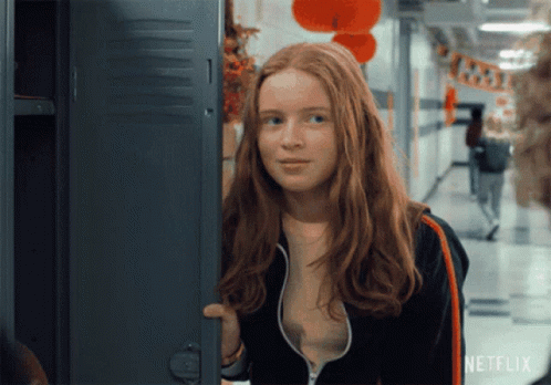 A Girl With Red Hair Is Standing In Front Of A Locker With Netflix Written On It GIF