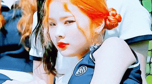 A Girl With Red Hair Is Wearing A Blue Shirt With The Letter T On It . GIF