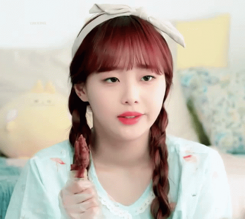 A Girl With Red Hair Is Wearing A Headband And Eating A Piece Of Meat GIF