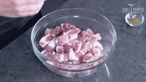 a glass bowl filled with chopped meat next to a small bowl of spices and a chili pepper logo