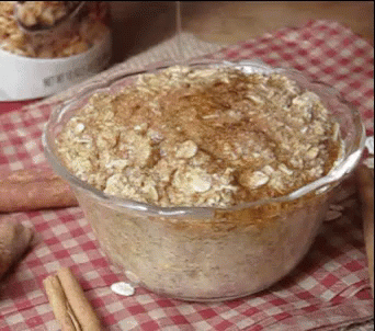 A Glass Bowl Filled With Oatmeal And Cinnamon Sticks On A Checkered Table Cloth . GIF