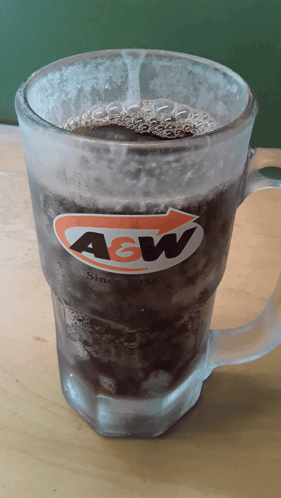 A Glass Of A&w Soda Is Sitting On A Wooden Table GIF