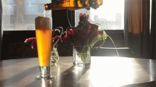 A Glass Of Beer Is Being Poured From A Bottle GIF
