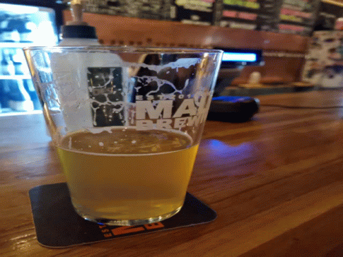 A Glass Of Beer Sits On A Coaster That Says Miami Brew GIF
