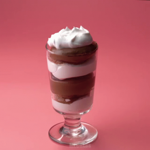 A Glass Of Chocolate Mousse With Whipped Cream On Top Of It GIF