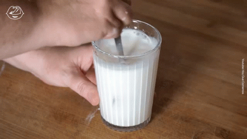 A Glass Of Milk Is Stirred With A Spoon GIF