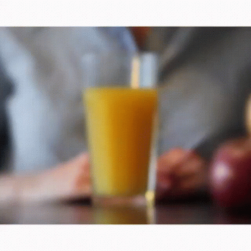A Glass Of Orange Juice With A Straw In It GIF