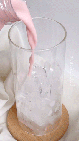 A Glass Of Pink Liquid Is Being Poured Into Ice GIF