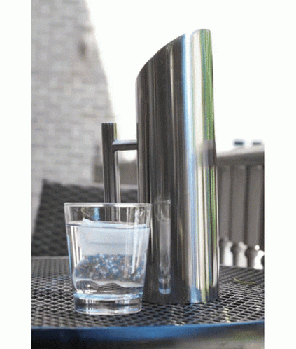 A Glass Of Water Sits Next To A Pitcher On A Table GIF