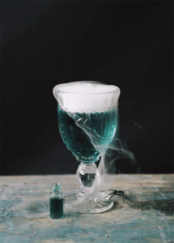 A Glass With Smoke Coming Out Of It Next To A Bottle GIF