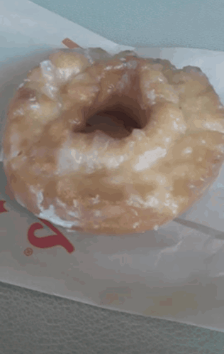 A Glazed Donut Is Sitting On A Piece Of Paper That Says ' S ' On It GIF