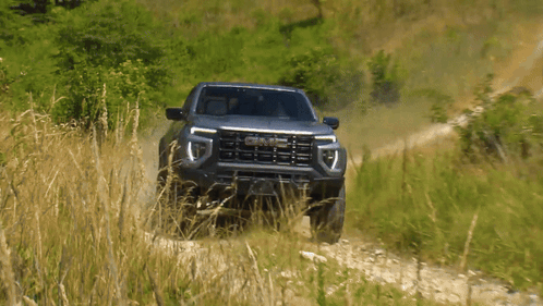 A Gmc Truck Is Driving Down A Dirt Path GIF