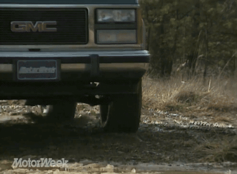 A Gmc Truck Is Driving Through The Mud GIF