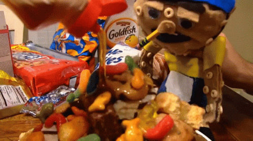 A Goldfish Cracker Is Being Poured Over A Pile Of Candy GIF