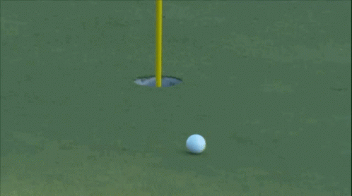 A Golf Ball Is Going Into A Hole On A Golf Course GIF
