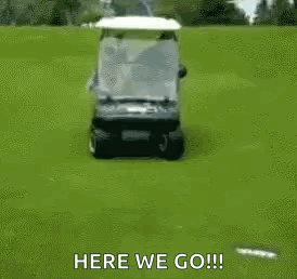A Golf Cart Is Driving Down A Golf Course With A Person Sitting On The Back . GIF