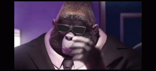 A Gorilla Wearing Sunglasses And A Suit And Tie Is Talking On A Cell Phone . GIF