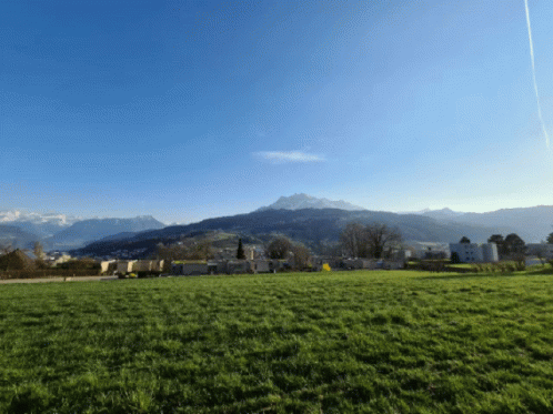 A Grassy Field With Mountains In The Background And A Blue Sky GIF