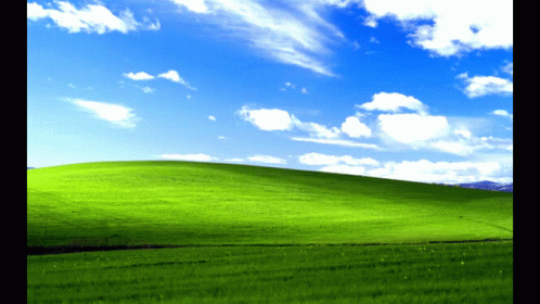 A Grassy Hill With A Blue Sky And White Clouds GIF