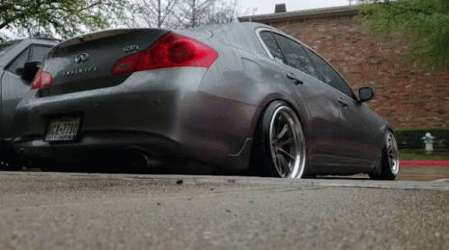 A Gray Infiniti Is Parked On The Side Of A Road GIF