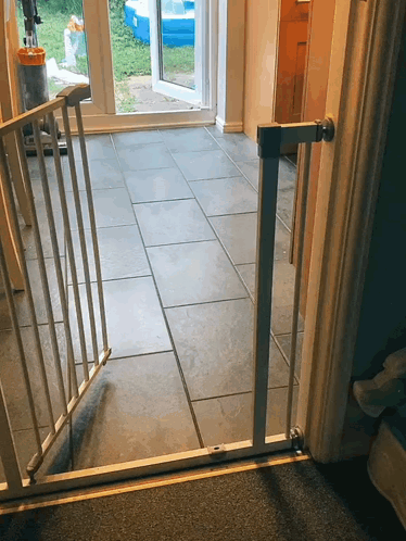 A Gray Tile Floor With A White Gate Between The Door And The Floor GIF