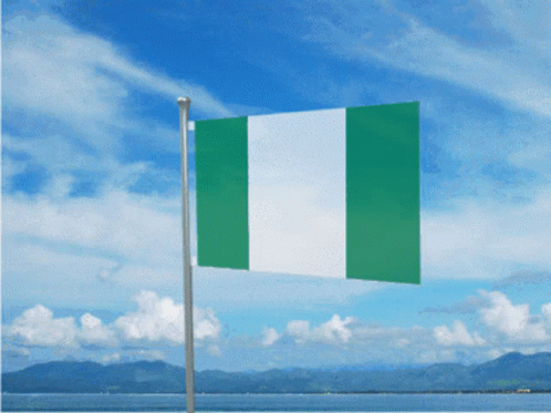 A Green And White Flag Is Flying In The Wind With Mountains In The Background GIF
