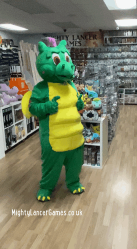 A Green And Yellow Dragon Mascot Giving A Thumbs Up In Front Of A Sign For Mighty Lancer Games GIF