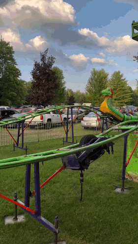A Green And Yellow Roller Coaster With A Snake In The Middle GIF