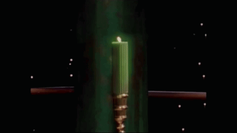 a green candle in a gold candle holder is glowing in the dark