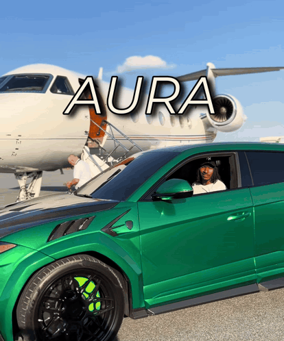 a green car is parked in front of a plane that says aura on it