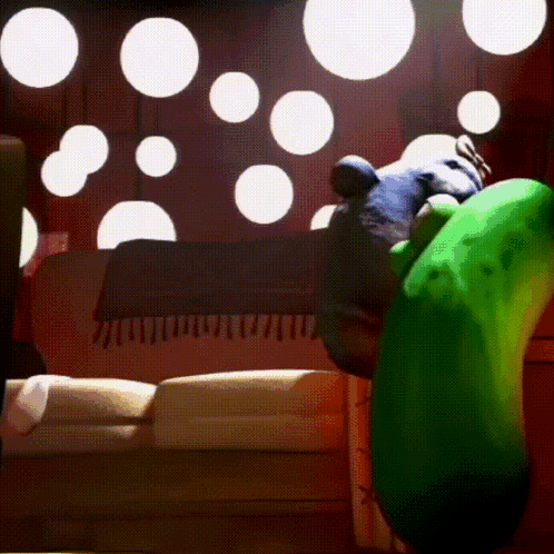 A Green Cartoon Character Is Sitting On A Couch In A Room GIF