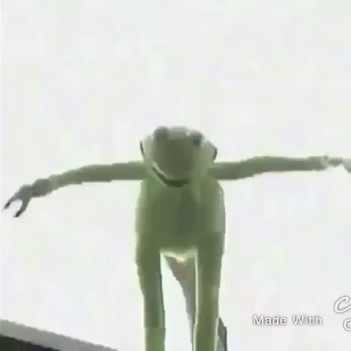 A Green Frog Is Standing On Top Of A Building In The Rain GIF