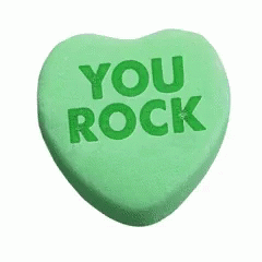 A Green Heart Shaped Candy With The Words `` You Rock '' Written On It . GIF